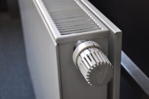 Nahaufnahme eines weißen Heizkörperthermostats an einem Heizkörper. Das Thermostat steht symbolisch für die Erneuerung und effiziente Steuerung der Heizung im eigenen Zuhause. Die Darstellung passt thematisch zur Online-Infoveranstaltung rund um Heizungserneuerung, klimafreundliche Wärmeversorgung und gesetzliche Vorgaben.