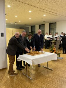 Mehrere Personen schneiden gemeinsam einen Kuchen beim Neujahrsempfang an.