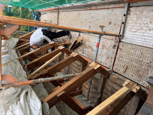 Zimmermann bei Arbeiten am Dachstuhl des Rathauses