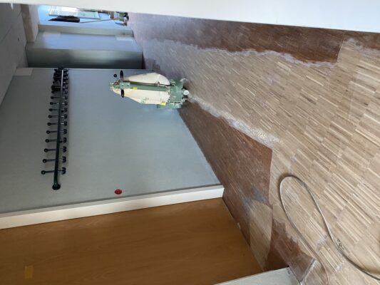 Flur mit abgeschliffenem Holzboden und Reinigungsmaschine während der Renovierungsarbeiten