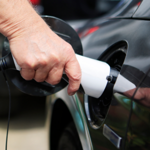 Hand lädt ein Elektroauto an einer öffentlichen Ladesäule