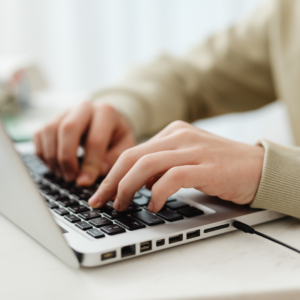 Person tippt auf einer Laptop-Tastatur und bucht einen Termin online.