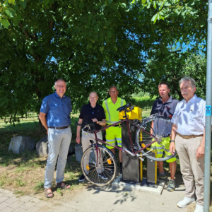 Vier Personen stehen an der neuen ADAC Radservice-Station in Ehrenkirchen. Ein Fahrrad ist an der Reparatursäule befestigt.