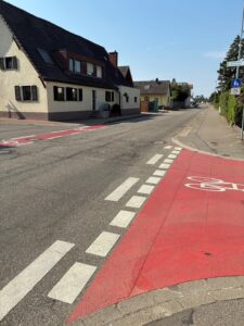 B 3 in Norsingen mit markiertem Radweg und angrenzenden Gebäuden