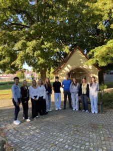 Gruppe junger Menschen vor einem Gebäude unter einem großen Baum